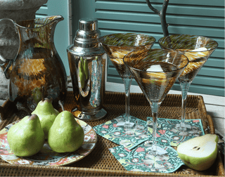 Cocktail shaker and glasses on a tray with pears and a pitcher.