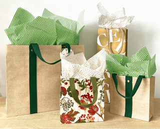 Four gift bags with different designs on a wooden surface